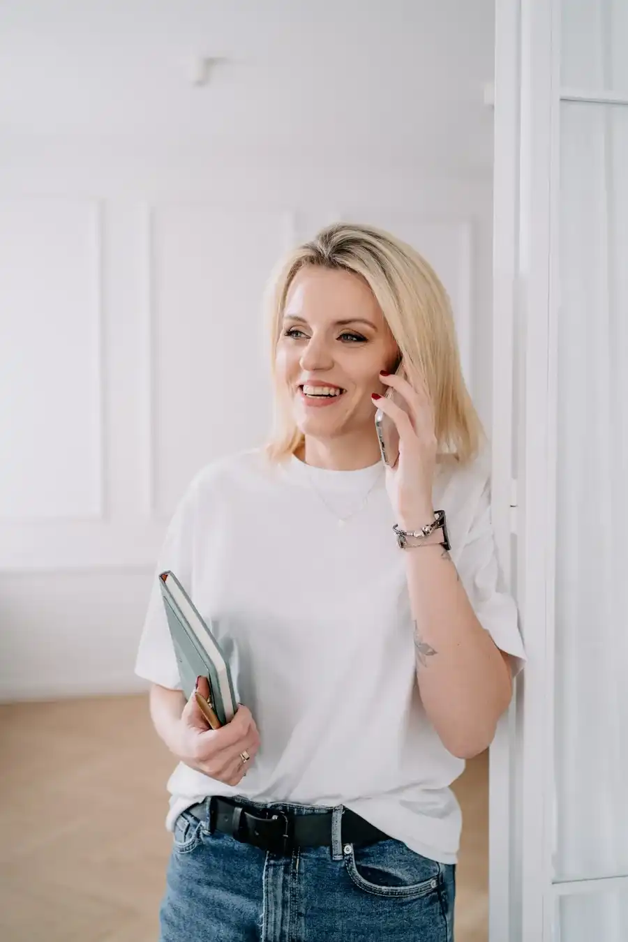 Stylistka wnętrz rozmawia przez telefon, trzymając notes